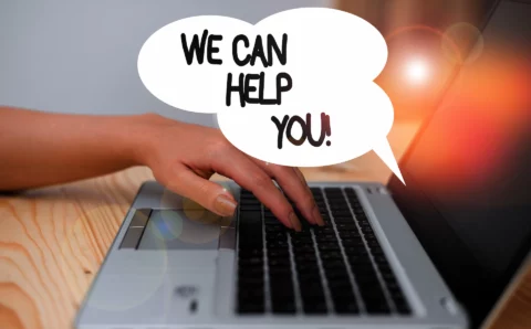 Hand over keyboard with we can help you in a speech bubble